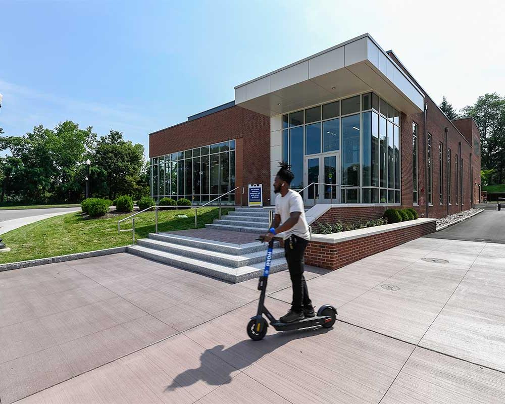 front entrance of the sloan performing arts center with student on scooter riding by the entrance